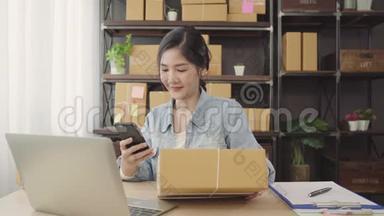 美丽的亚洲年轻企业家，女企业家，中小企业检查产品的股票扫描QR代码，在家工作。